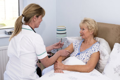 nurse injecting the right shoulder of an elderly woman